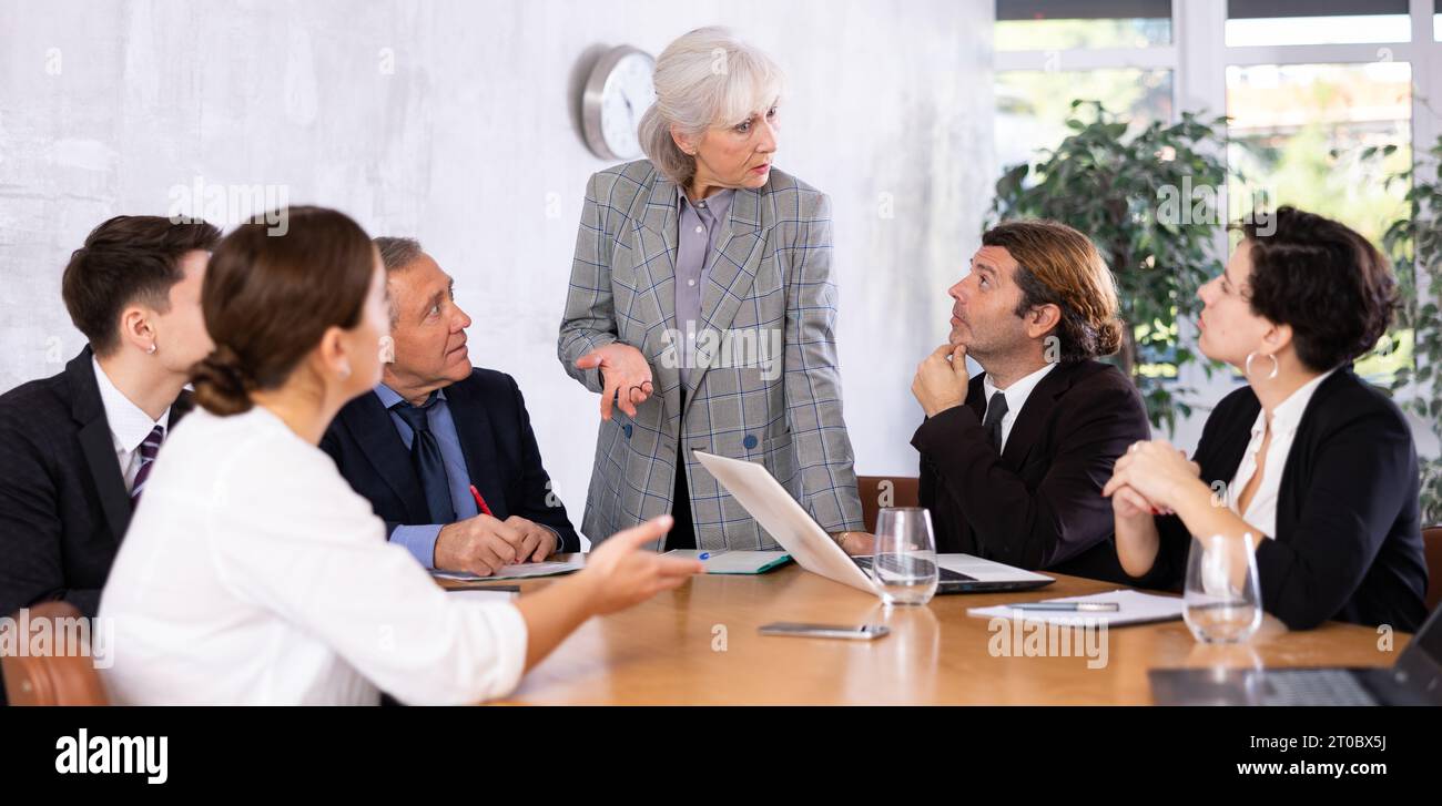 Experienced female businesswoman discussing project with colleagues Stock Photo