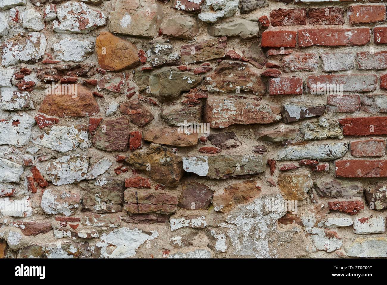 A weathered and aged stone brick wall, showing signs of decay and