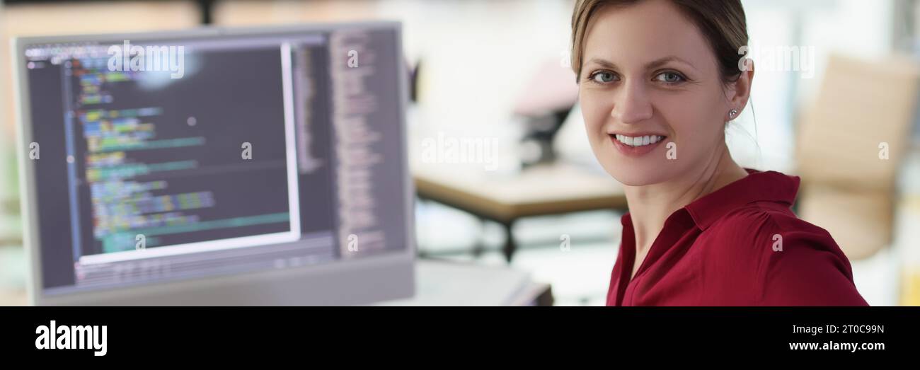 Smiling woman app developer writes code in company office Stock Photo