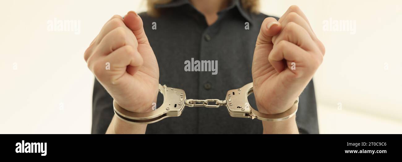 Woman with handcuffs on wrists in prison cell closeup Stock Photo
