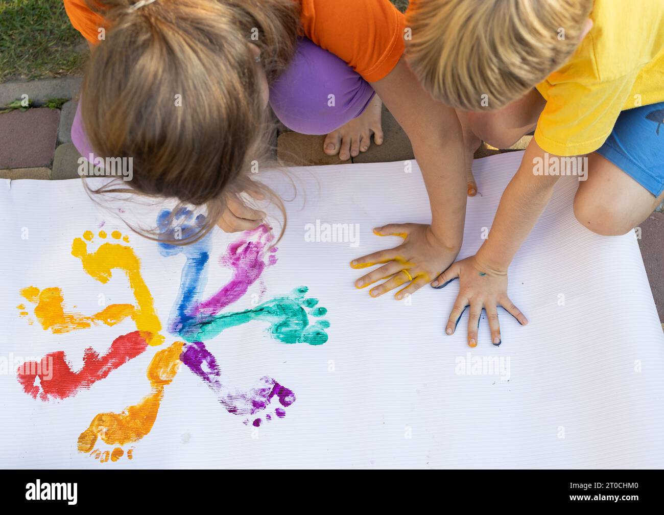 Colorful prints of children's painted hands and feet. Brother, sister. friends having fun, creative concept. Interesting happy childhood Stock Photo