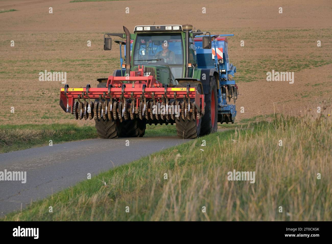Landwirtschaft-Trecker mit Drillmaschine und Egge drillt Gerste fuer