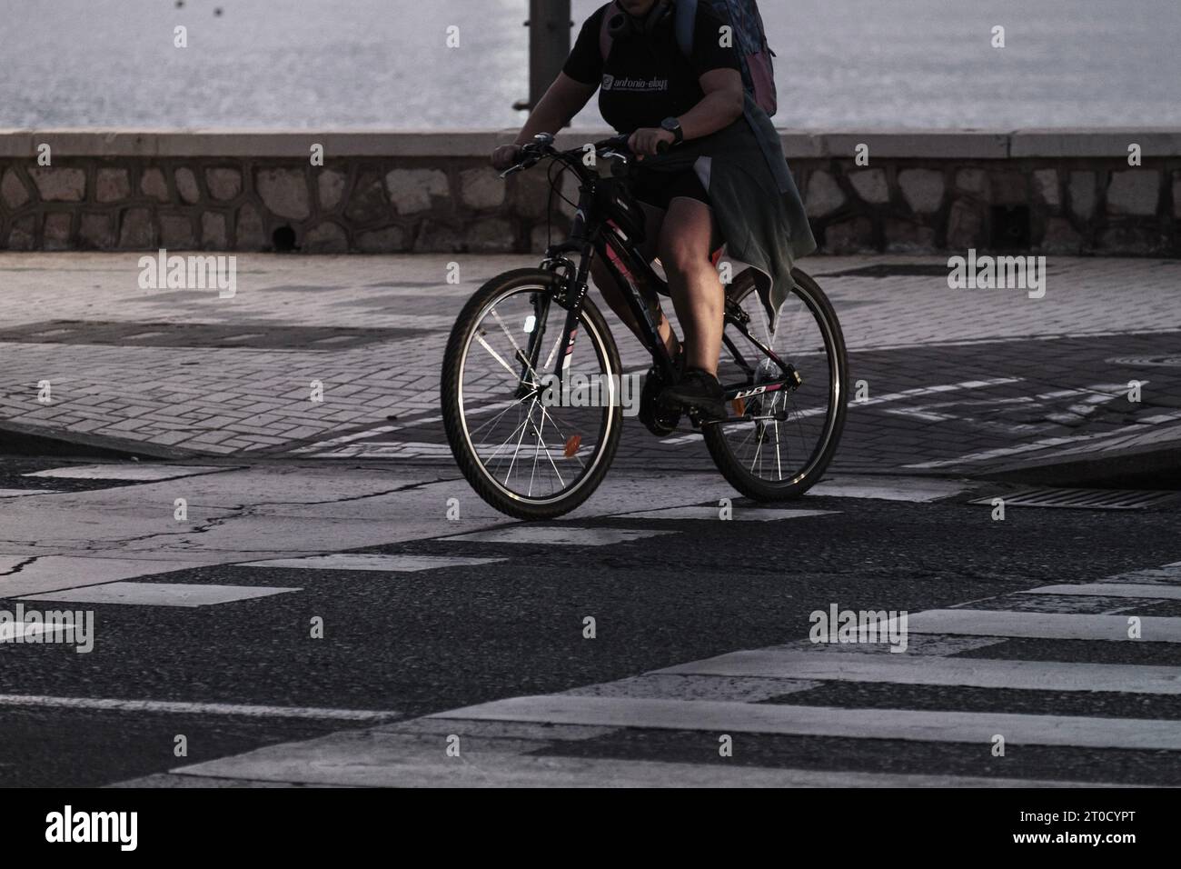 People doing sports on the promenade, Man riding a bike crossing the pedestrian crossing bike lane Stock Photo