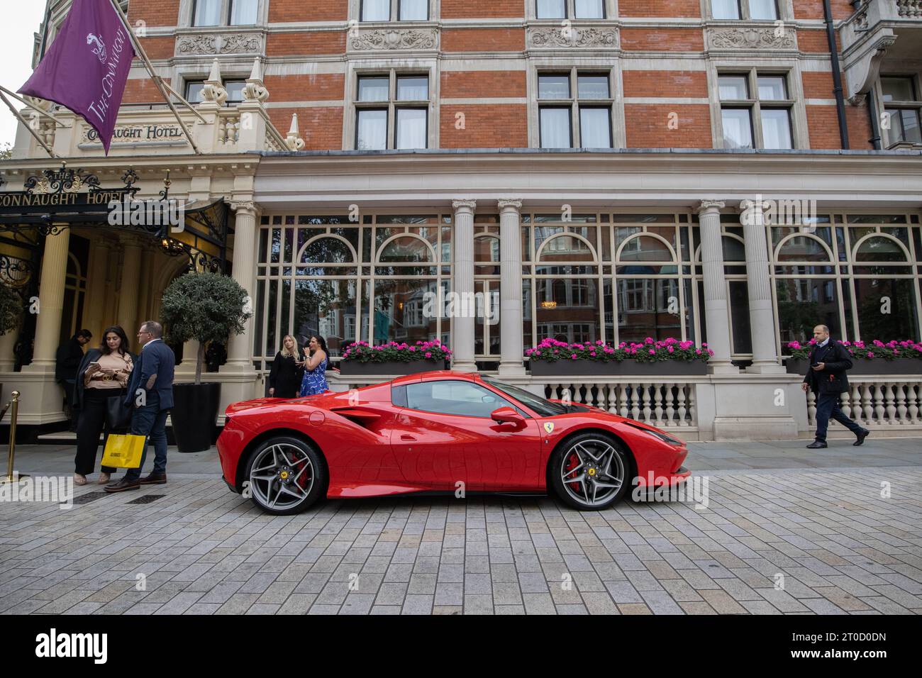 Red Ferrari parked outside the Connaught Hotel, luxury hotel in Mayfair, London, UK Stock Photo