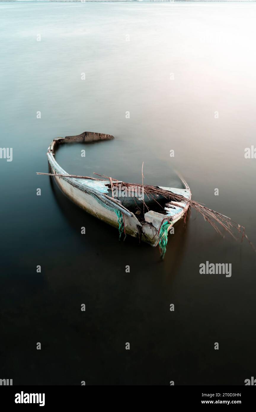 An abandoned boat, half-submerged in a lake Stock Photo
