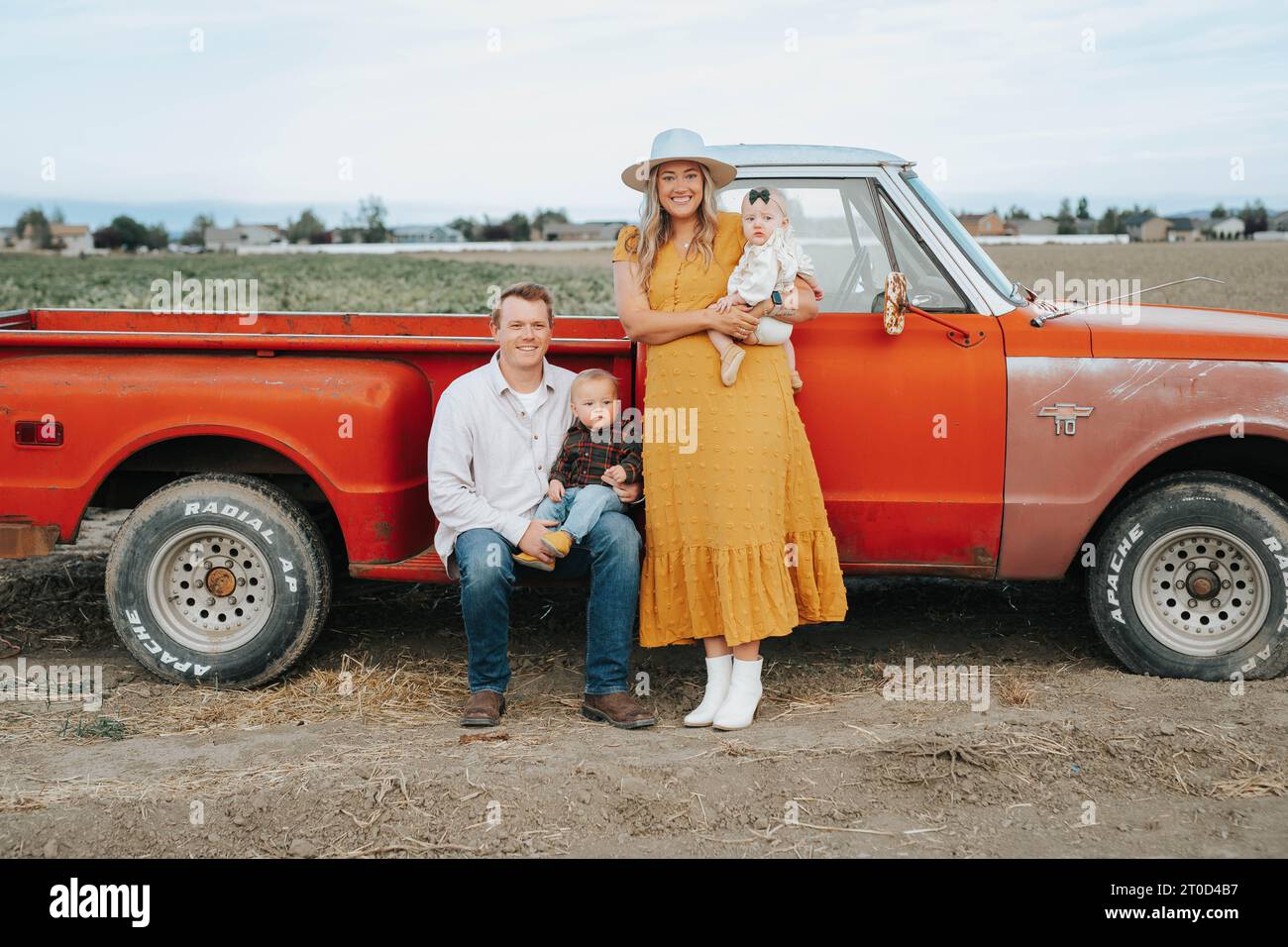 Family of four by old red truck at corn maze Stock Photo