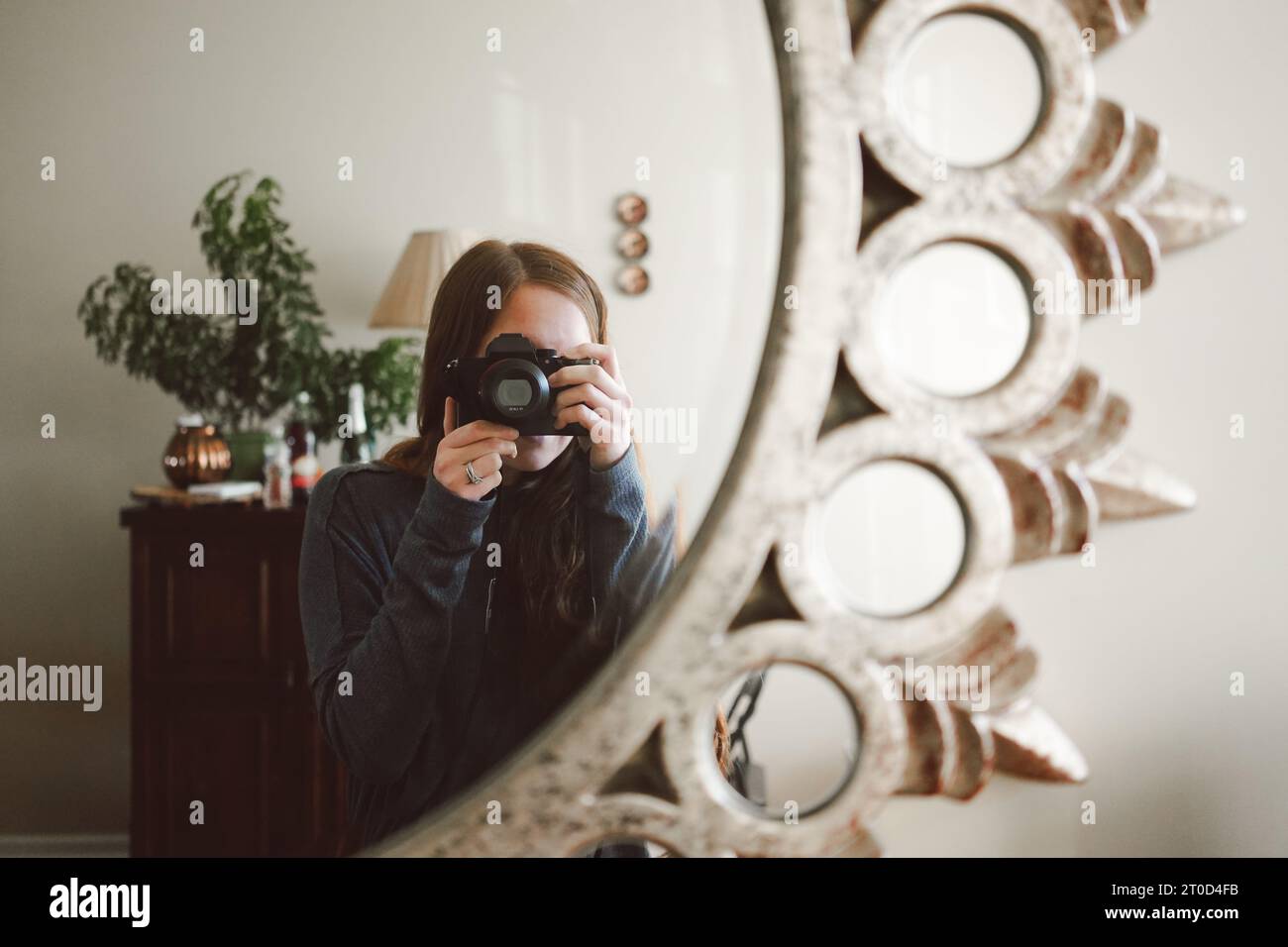 Woman captures a selfie in a mirror with DSLR camera Stock Photo