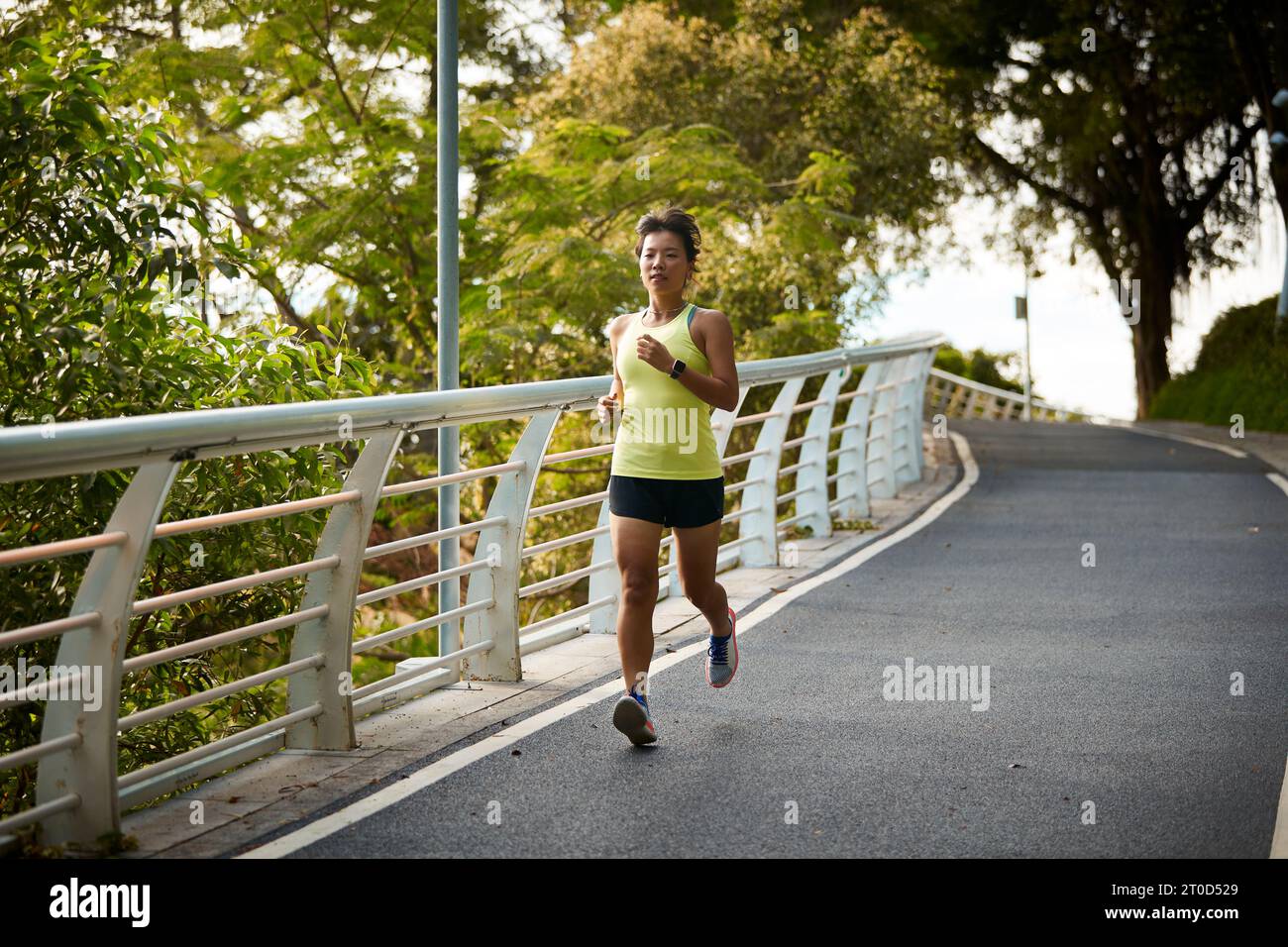 young asian woman running jogging exercising outdoors in city park Stock Photo