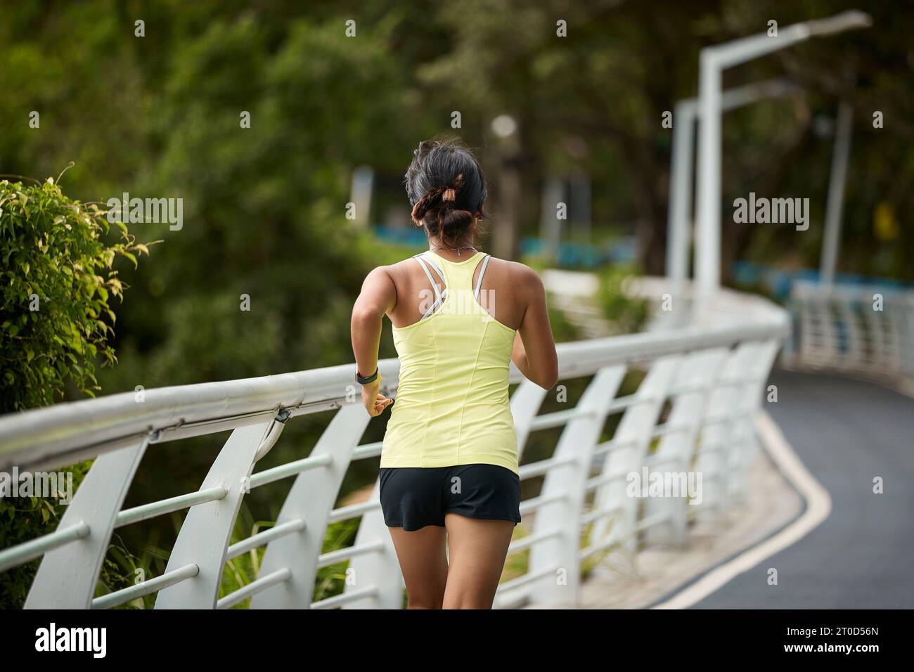 rear view of young asian woman running jogging exercising outdoors in city park Stock Photo