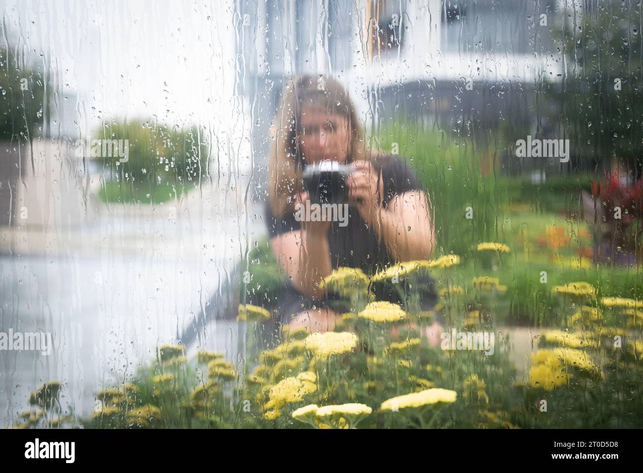 Portrait of woman taking photographs of flowers outside. Stock Photo