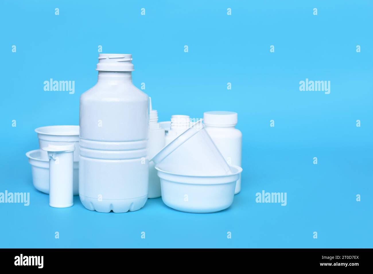 Different empty plastic waste packages on blue background with negative space Stock Photo
