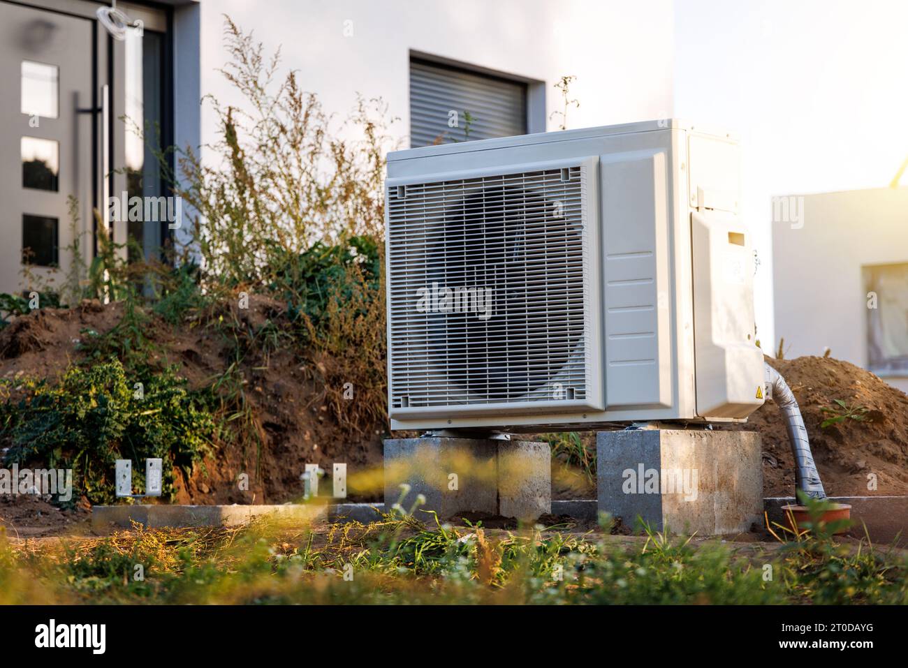 Heat pump outdoor unit in front of a newly built single family house Stock Photo
