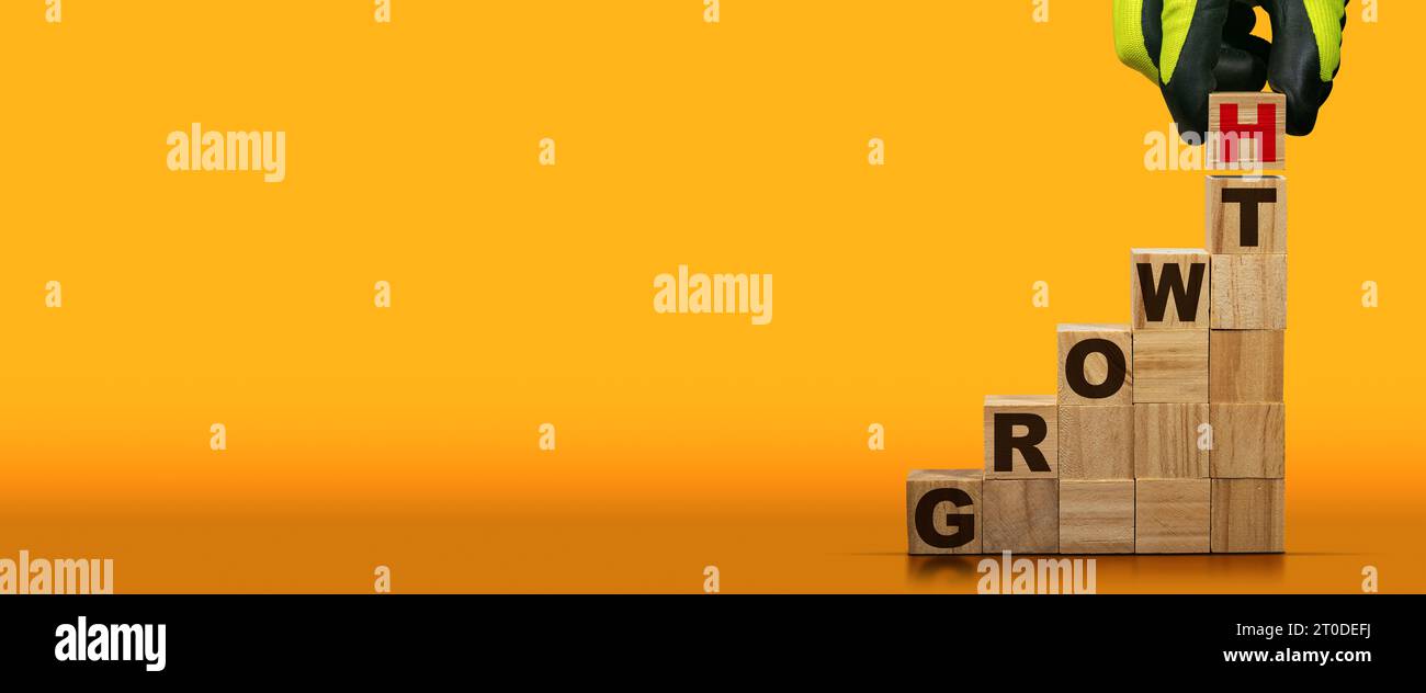 Gloved hand arranging wood blocks with text Growth on an orange and ...