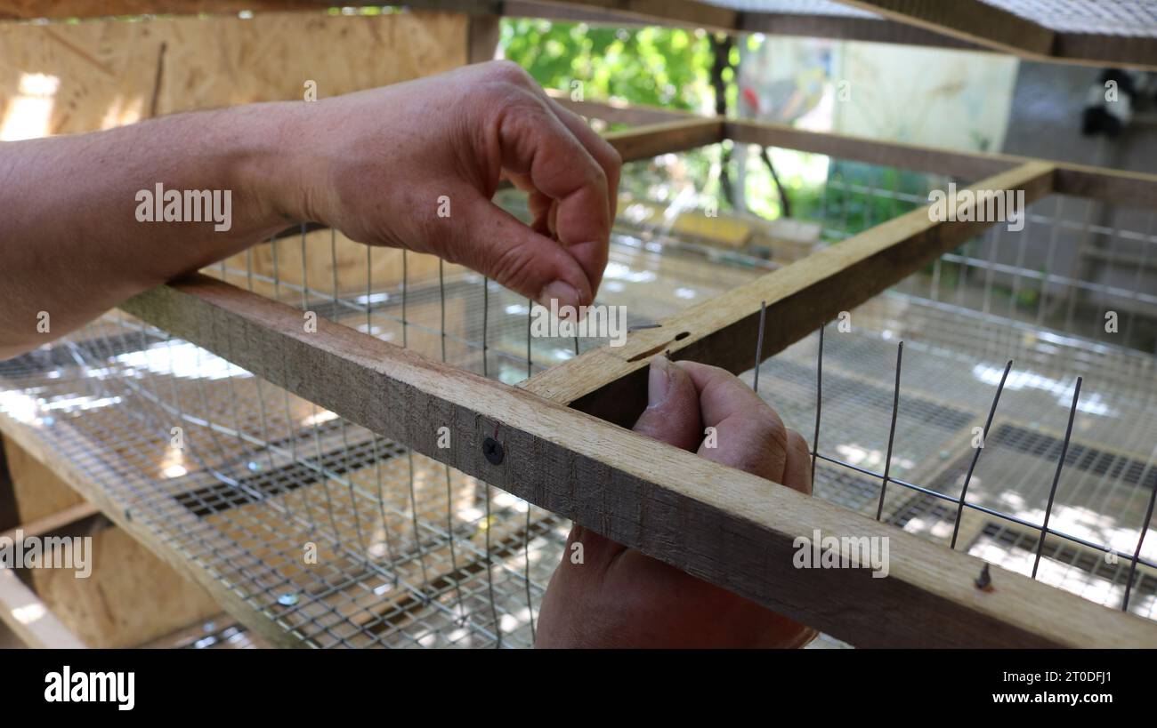 male hands bend the ends of the wire in the process of creating a cage ...