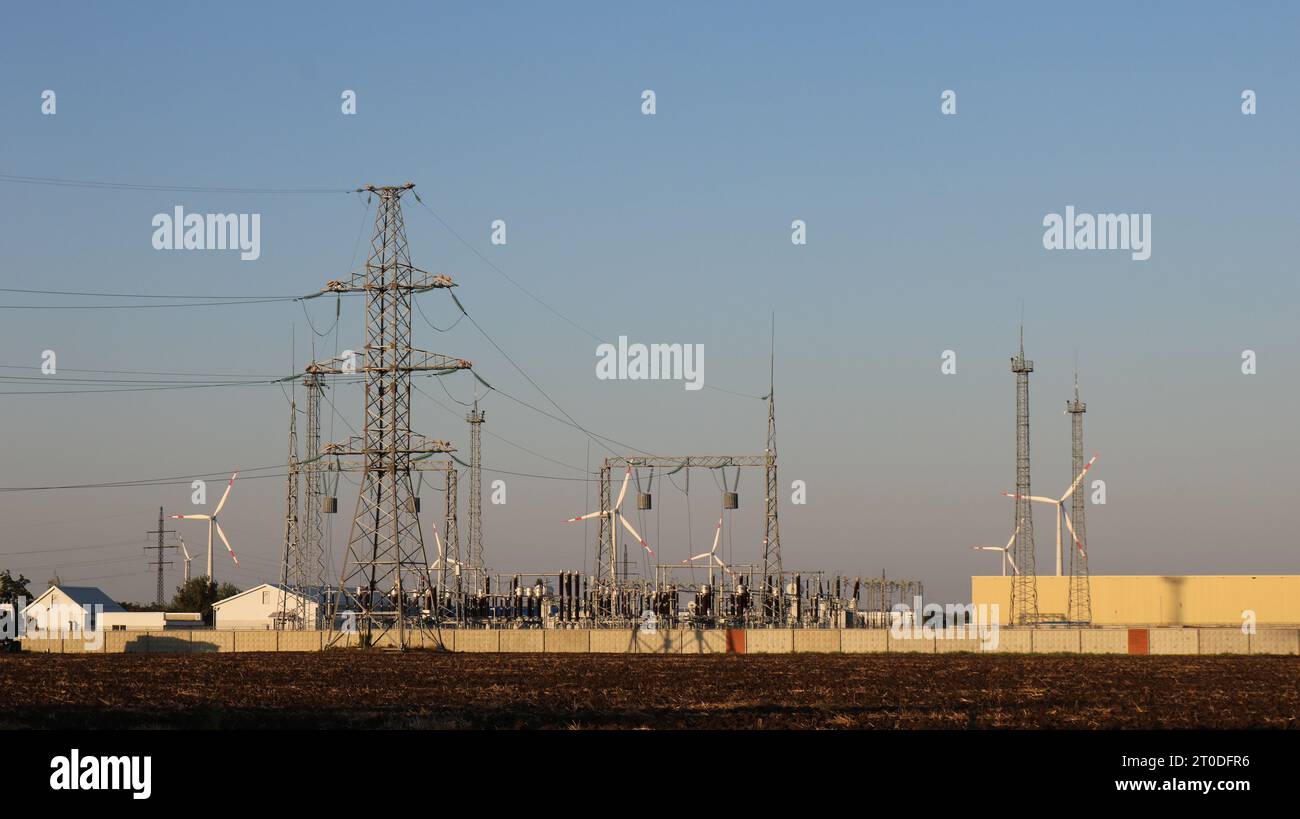 power plant with high voltage lines and wind generators in a field at a ...