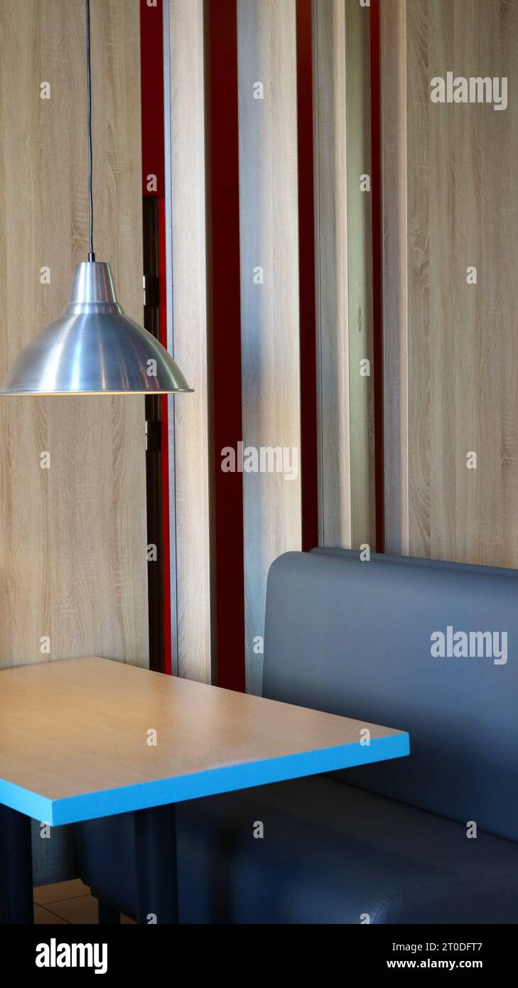 vertical picture of an empty table in a cafe under a hanging lamp, a place for a meeting or work in a restaurant or cafeteria without people Stock Photo