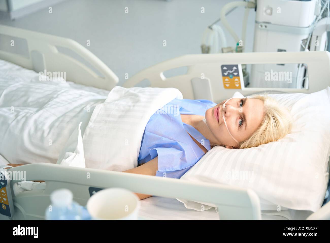 Beautiful woman after surgery lies in room with modern equipment Stock