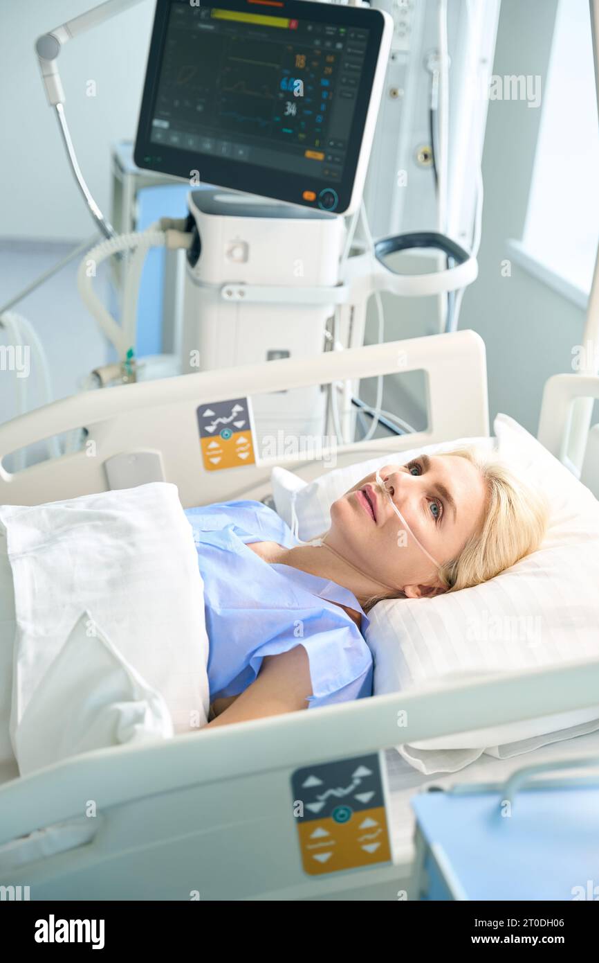 Beautiful lady after surgery lies in room with modern equipment Stock