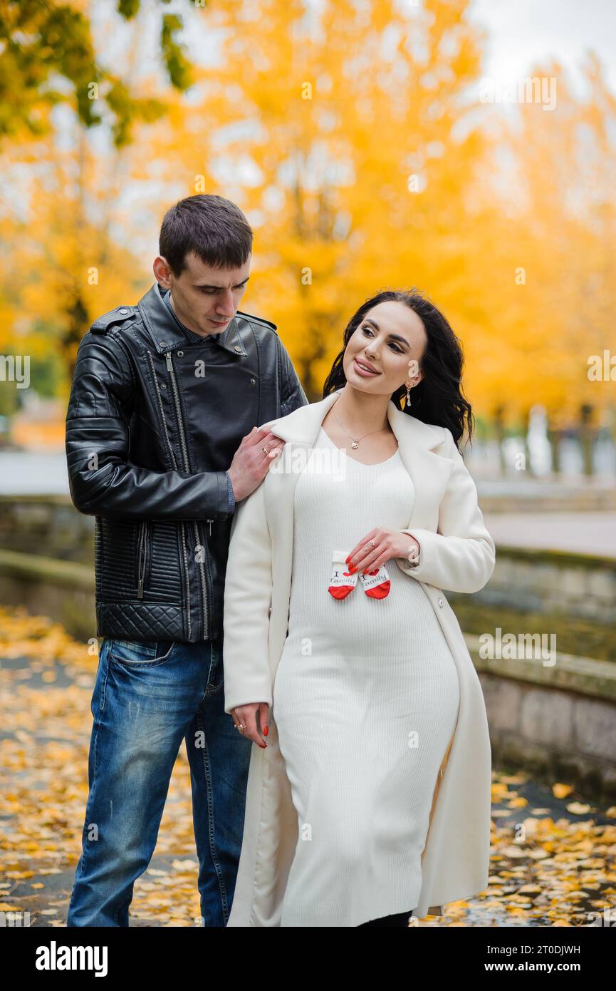 A man hugs his pregnant wife. Woman holding baby's socks near belly ...