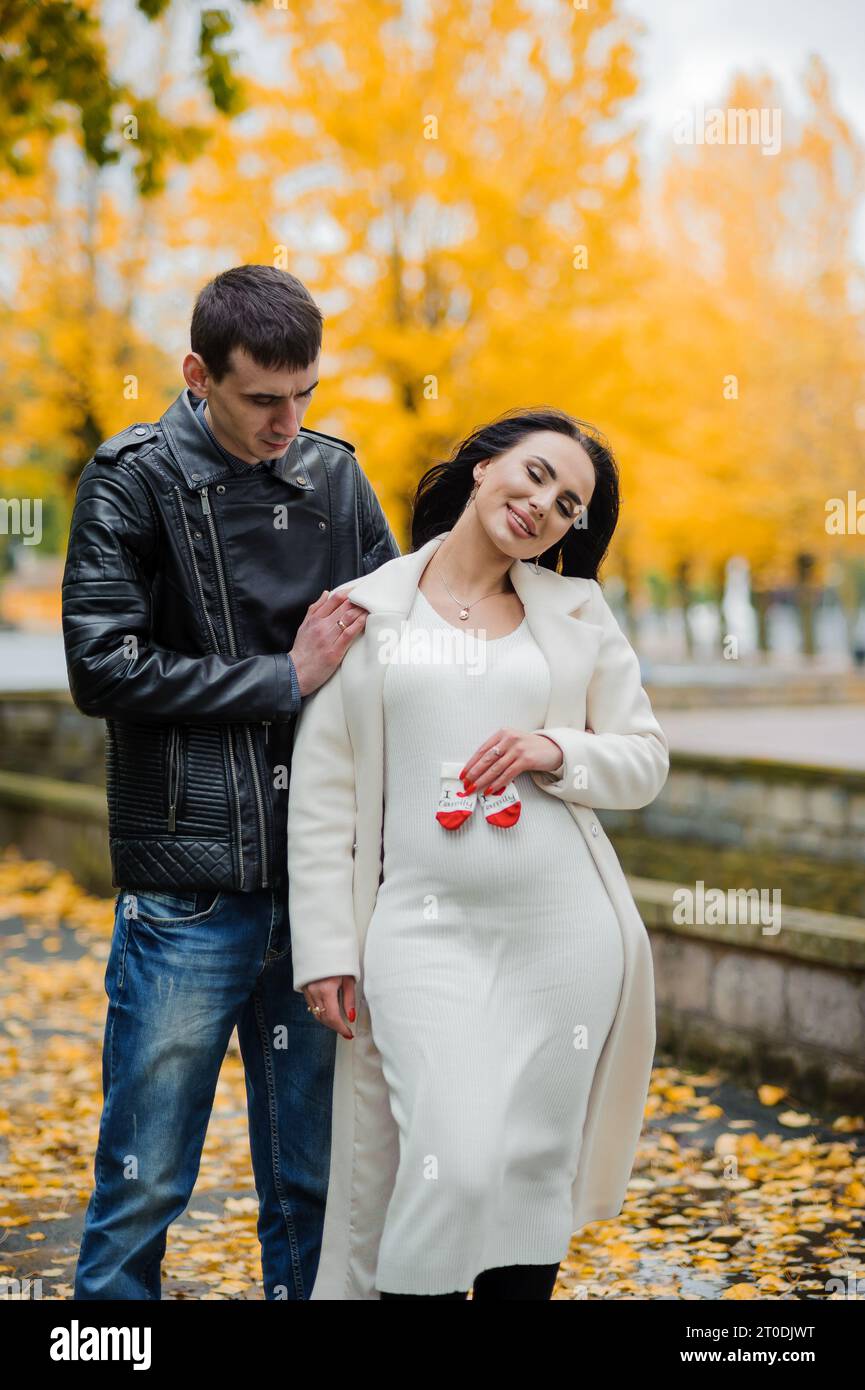 A man hugs his pregnant wife, woman holding baby's socks near belly ...