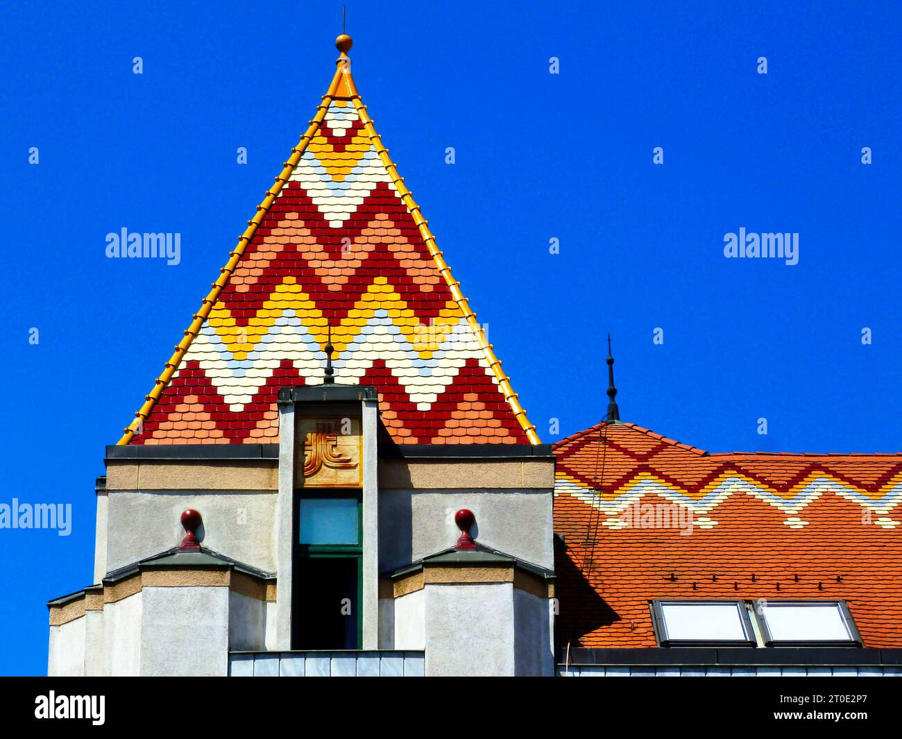 sloped enamel coated clay tile roof. colorful orange, yellow, red and white geometric pattern. ornamental decorative old building in Pecs, Hungary Stock Photo