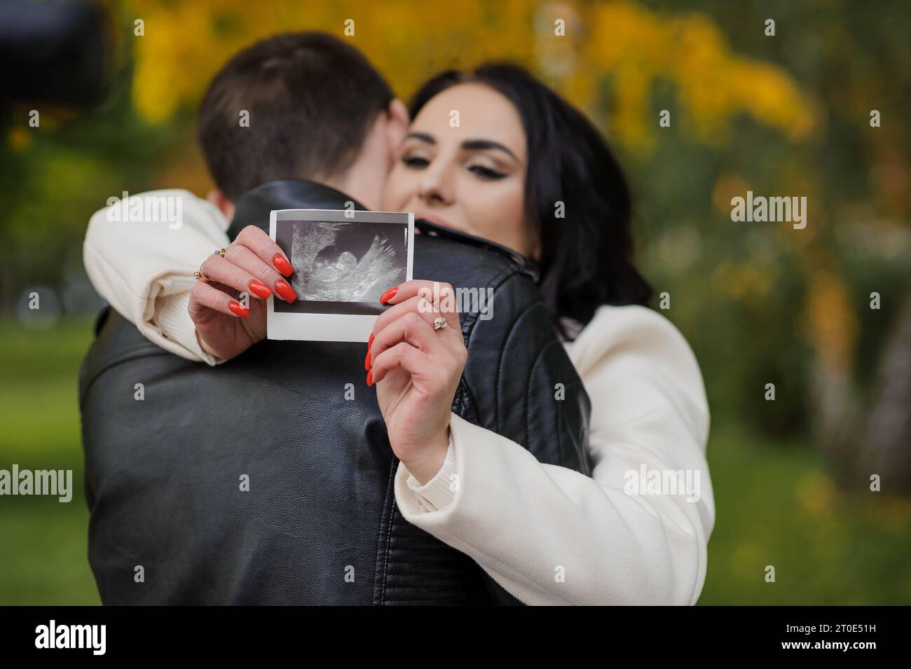 A man hugs his pregnant wife. Woman holding ultrasound photo of baby ...