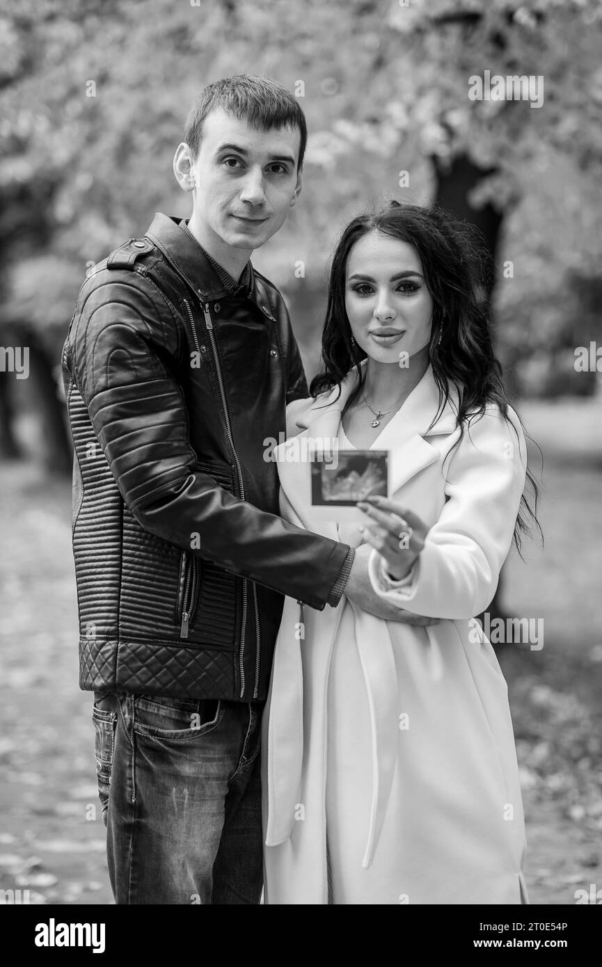 A man hugs his pregnant wife. Woman holding ultrasound photo of baby ...