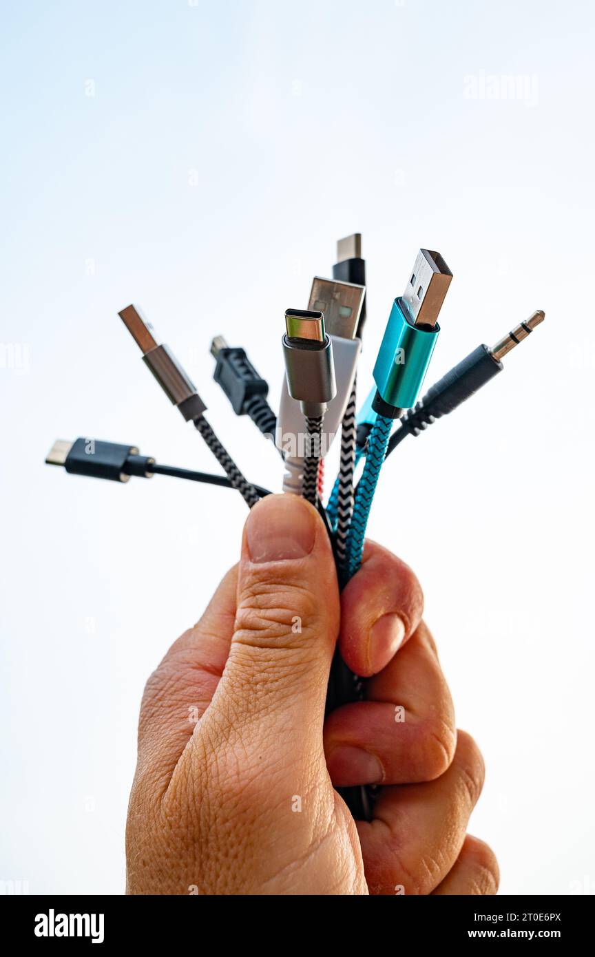Hand holding various types of cables with USB plugs, evolution and