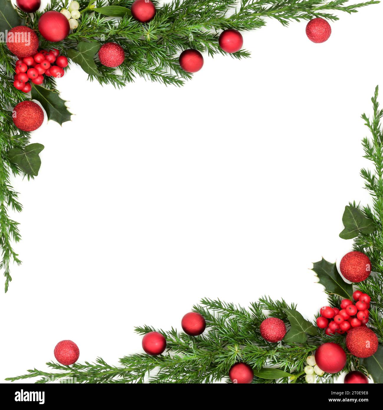 Christmas background border with poinsettia flower on parchment paper with  red and gold bauble decorations, holly, mistletoe, ivy, fir and pine cones  on oak Stock Photo