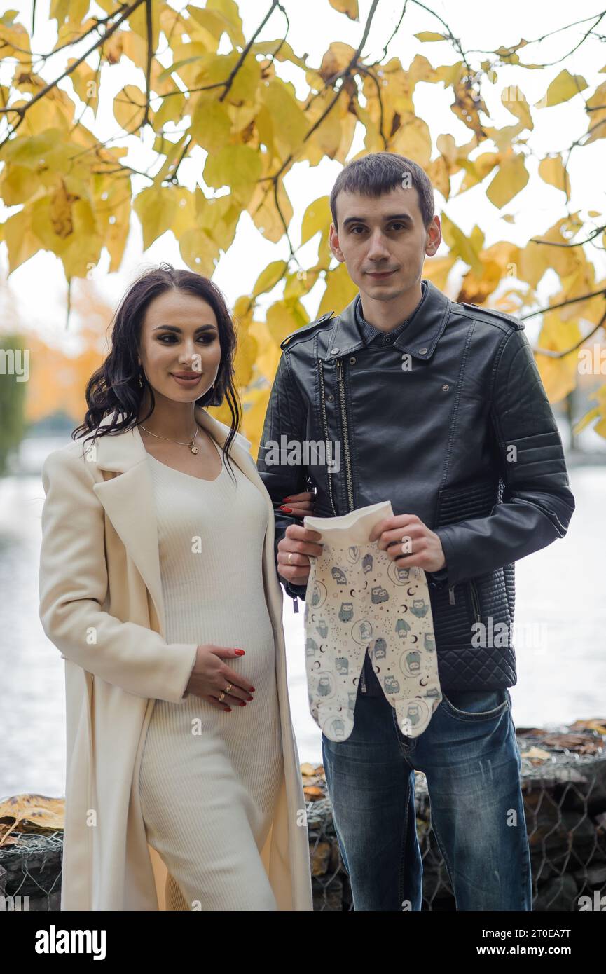 A man hugs his pregnant wife. Woman holding baby's pants Stock Photo ...
