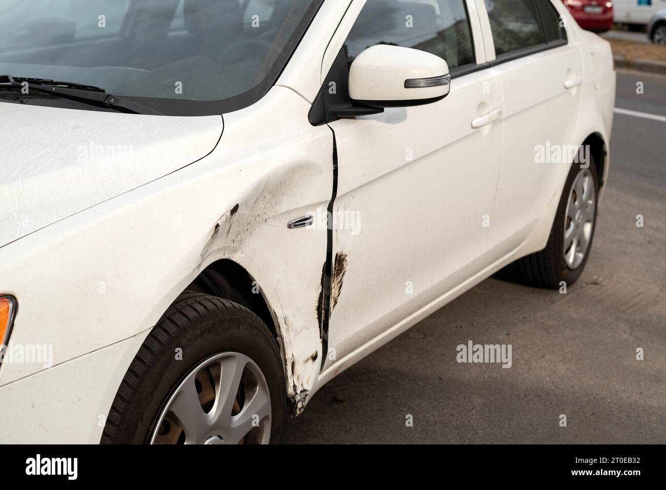 Damaged side door on a white car after a small traffic accident requiring a repair Stock Photo