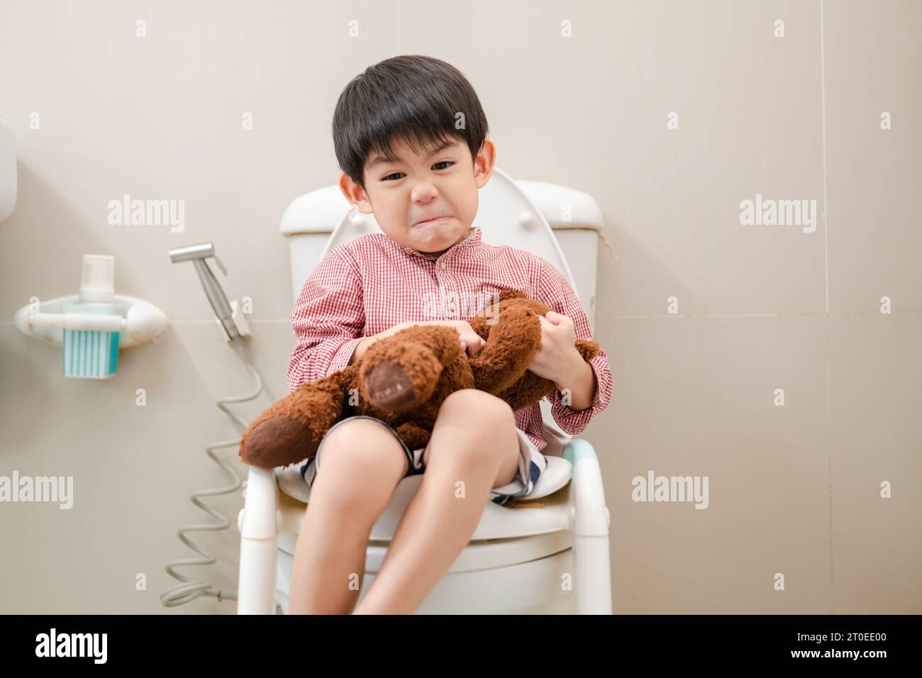 Asian boy Sitting on the toilet bowl in hand holding teddy bear Stock ...