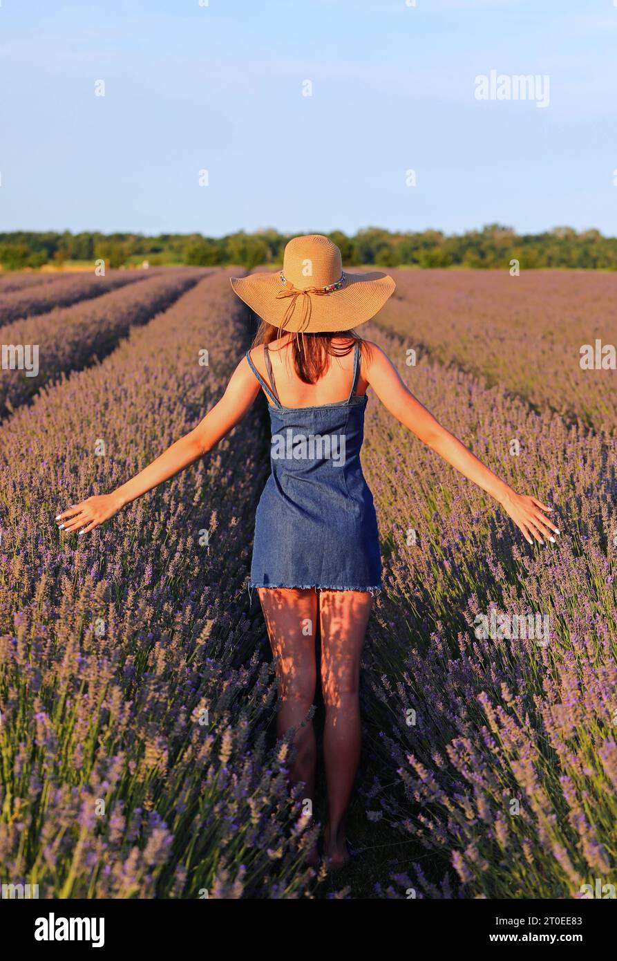 young slender top model girl in jeans dress and miniskirt and straw hat ...