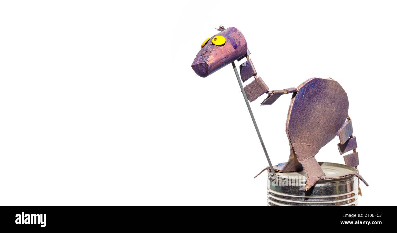 Cute cardboard dinosaur made by a child. Isolated purple dinosaur with yellow eyes and funny facial expression. DIY papercraft project ideas or kids c Stock Photo