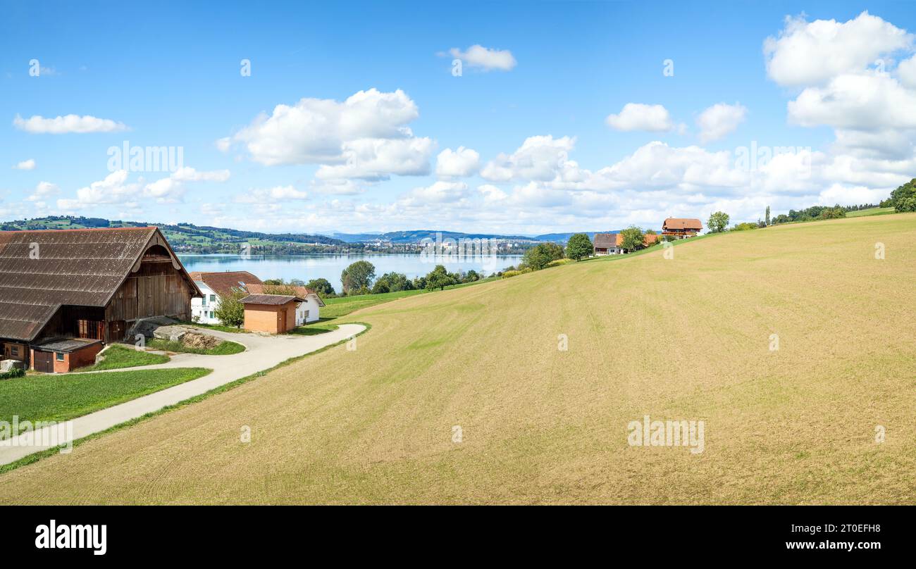 Scenic Swiss countryside with lake, panorama. Beautiful touristic summer scenery in Central Switzerland. Lake Sempach with farms and far off rural vil Stock Photo