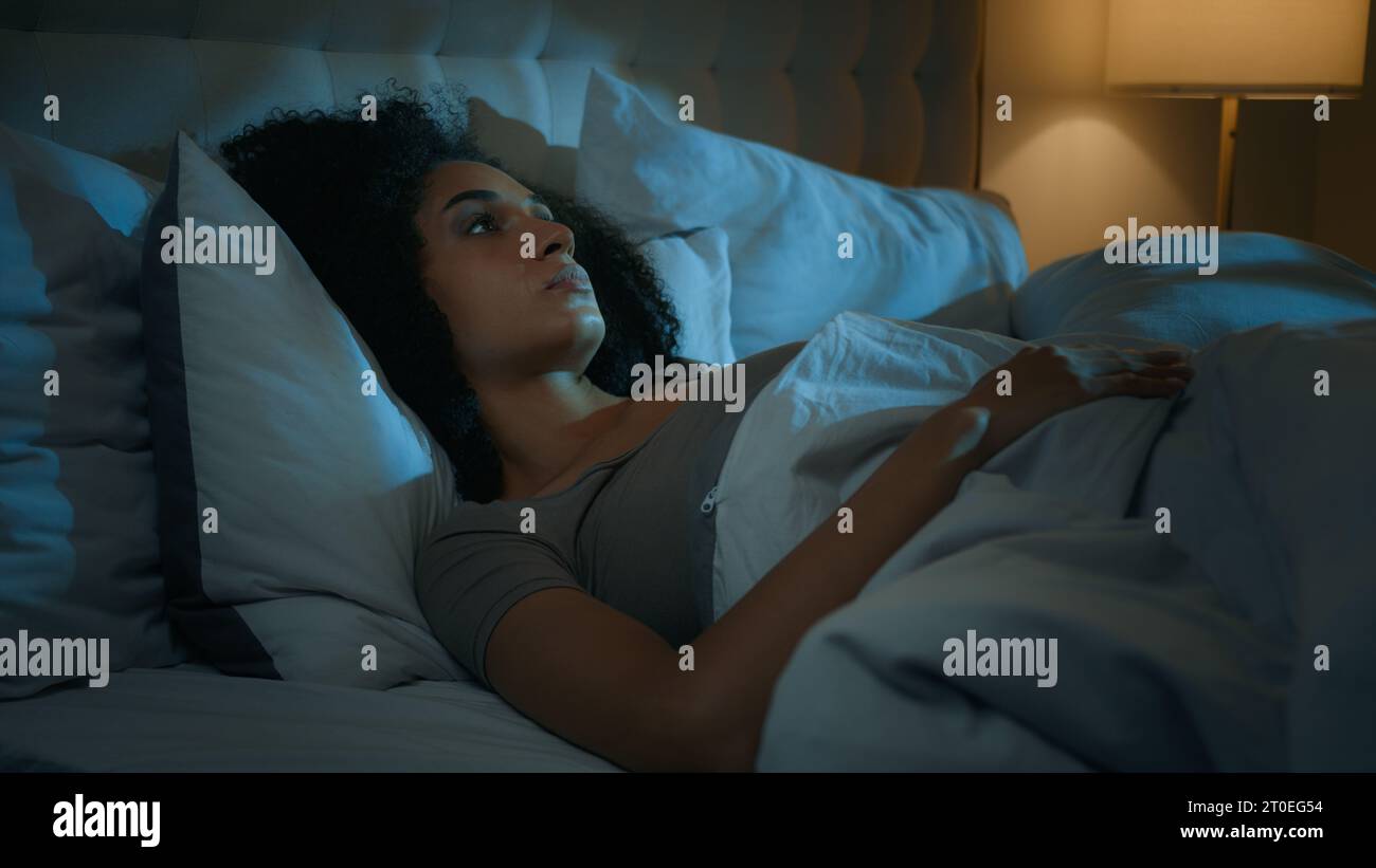 Noisy neighbours problem annoyed African American woman lying in bed