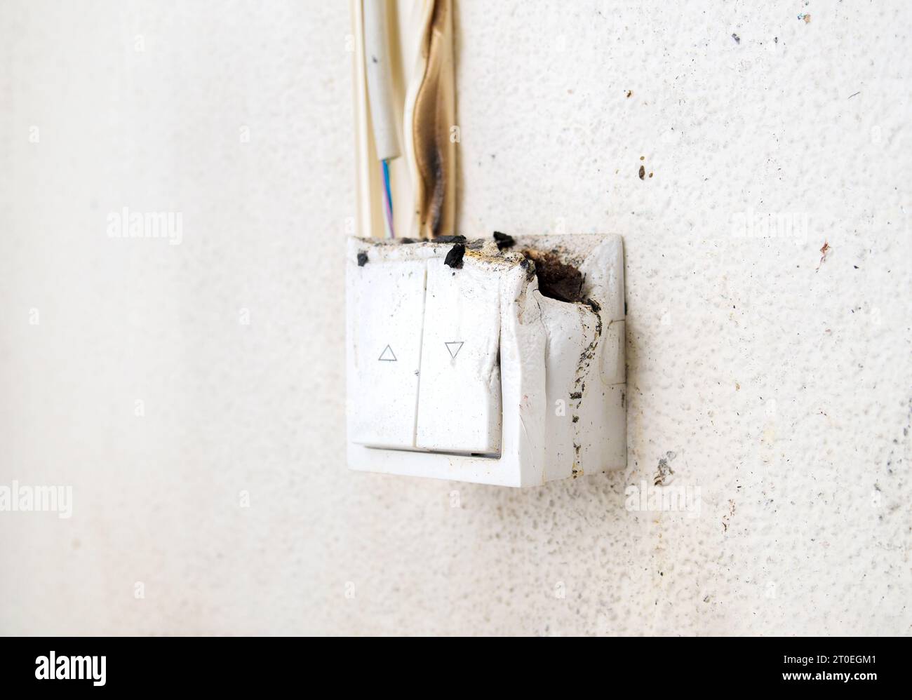 Melted light switch with fire damage, close up. Light regulator mounted on wall caught on fire