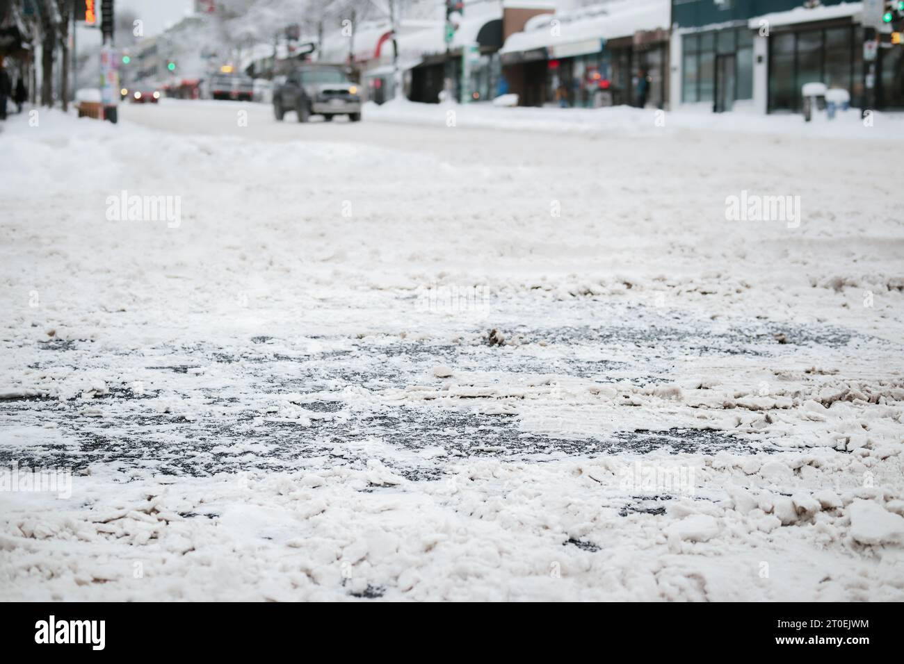 Snow covered city intersection, close up. Low angle view of main road not serviced or plowed with ice and slush. Stay at home and don't travel advice. Stock Photo