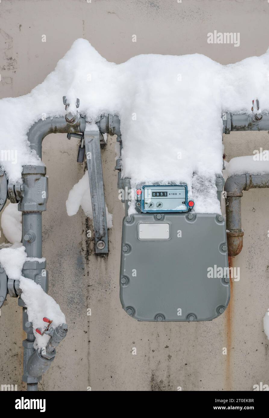 Snow covered natural gas line meter of building or home. High energy consumption in cold temperature.  Outdoor meter measuring the usage number in cub Stock Photo