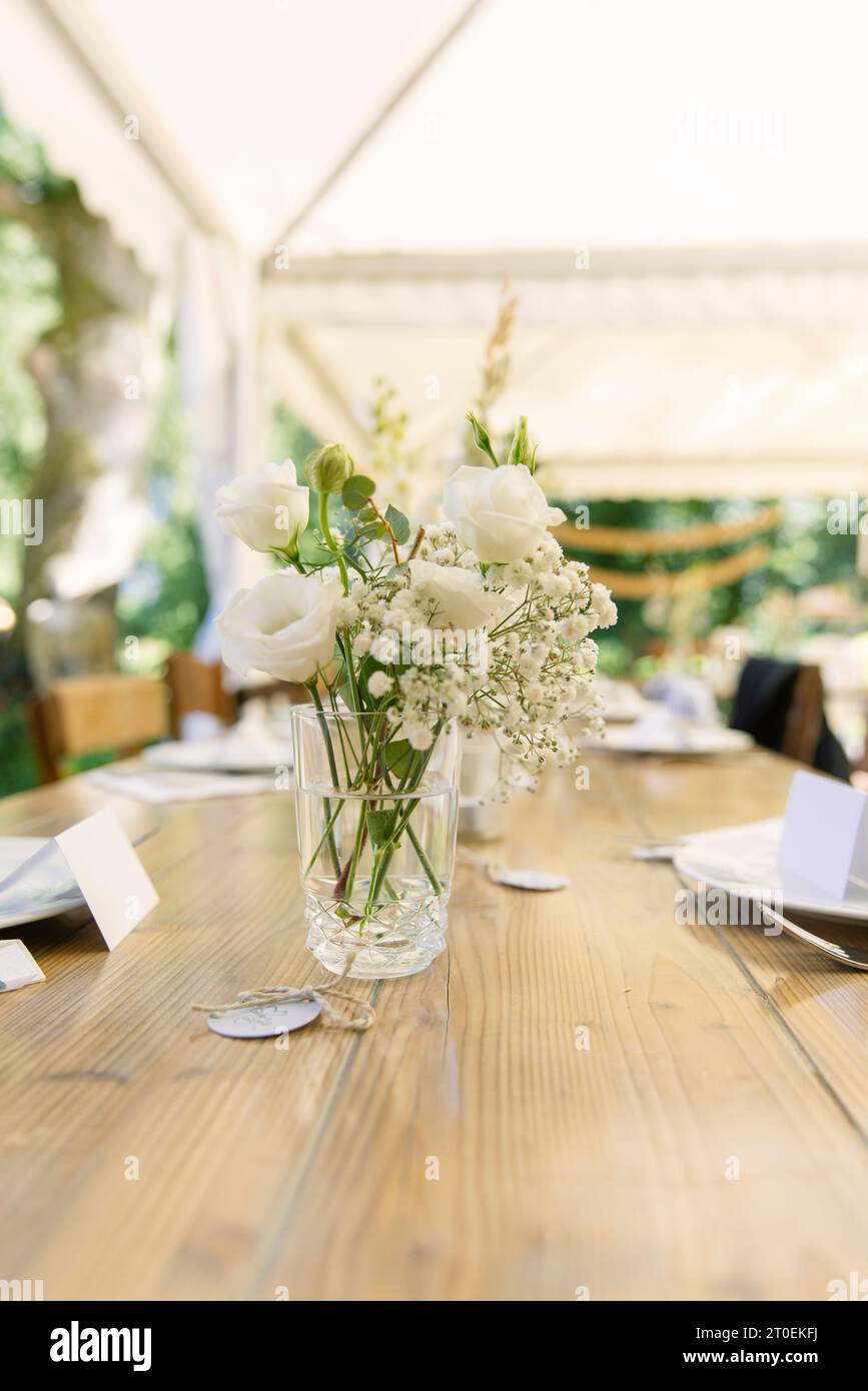 Wooden table set with white bouquet of flowers Stock Photo