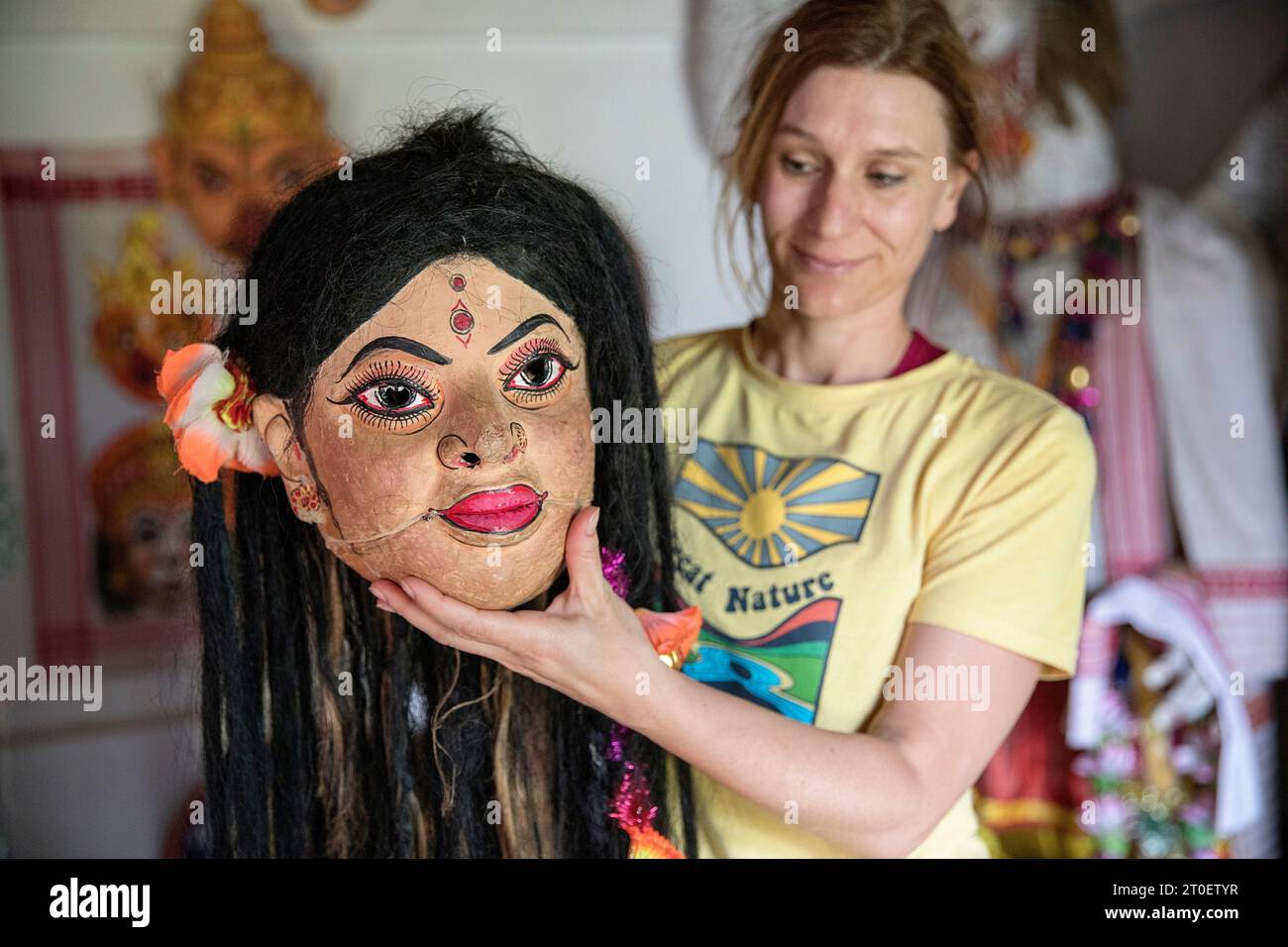 Caucasian woman holding beautiful traditional mask in her hand in workshop of world famous mask maker Hem Chandra Goswami, Majuli, Assam, India Stock Photo
