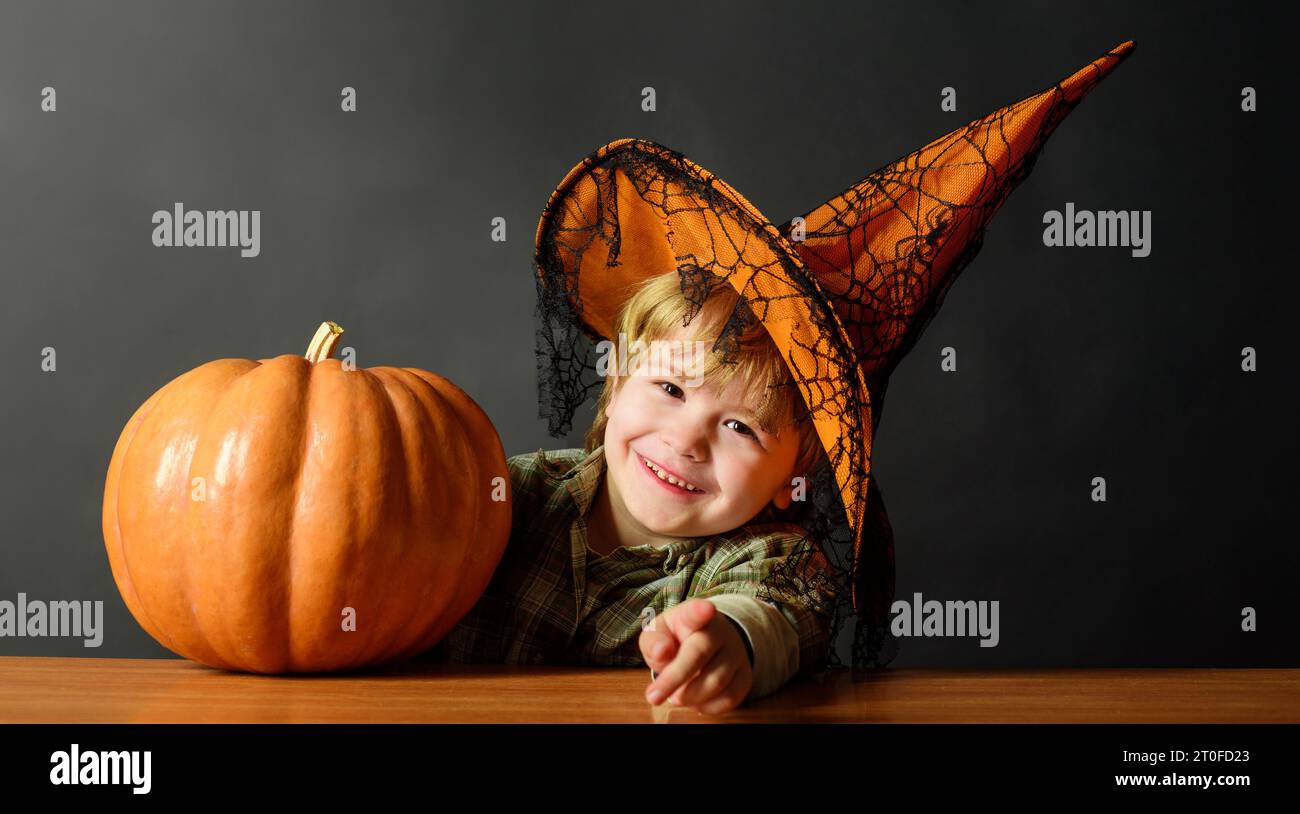31 October. Halloween party. Smiling child boy in witch hat with pumpkin. Preparation for Halloween holidays. Cute kid in Halloween costume with jack Stock Photo