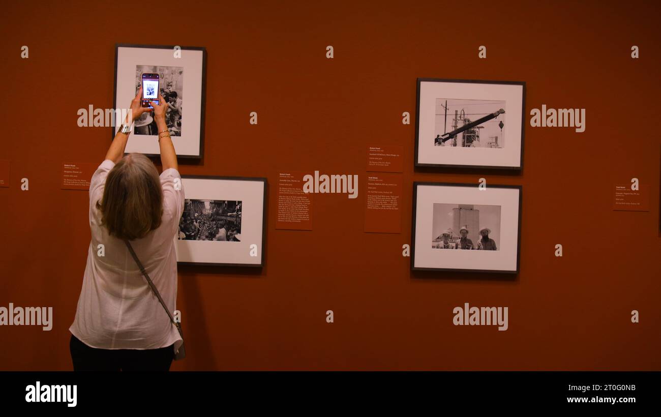 Houston, Oct. 8. 7th Jan, 2024. A woman tries to take a photograph at the preview of a photo exhibition titled Robert Frank and Todd Webb: Across America, 1955 at the Museum of Fine Arts, Houston, Texas, the United States, on Oct. 6. 2023. A total of 100 photographs chart the cross-country journeys of two photographers, who each captured singular views of America in the mid-20th century, during the exhibition here from Oct. 8, 2023 to Jan. 7, 2024. Credit: Xu Jianmei/Xinhua/Alamy Live News Stock Photo