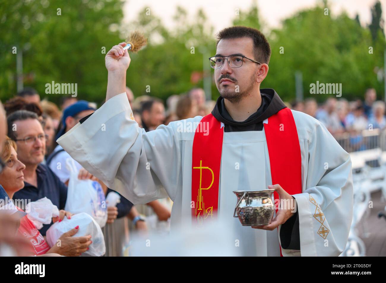 A priest blessing religious articles of the faithful after the evening Holy Mass in Medjugorje. Stock Photo