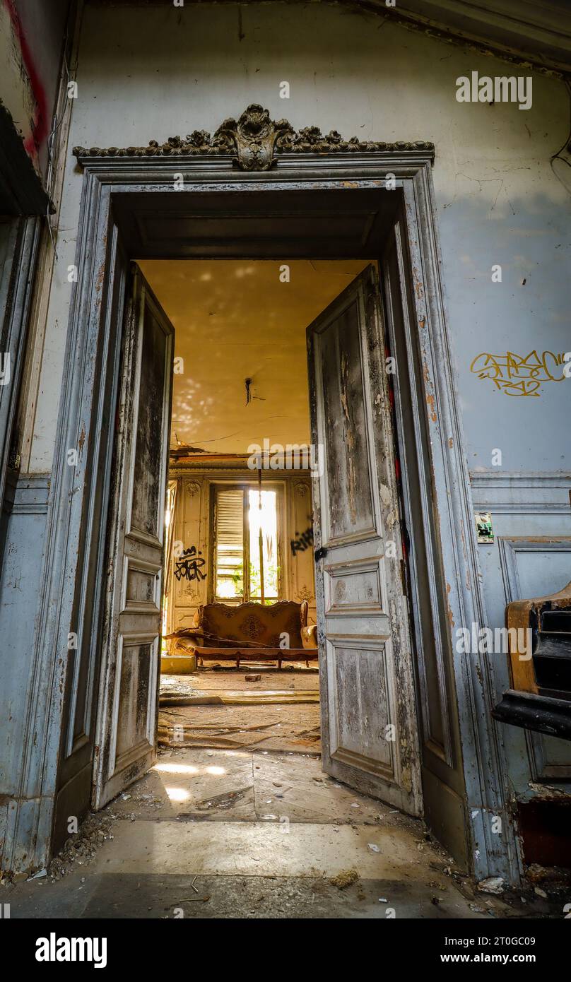wooden doorway with an old sofa in an abandoned mansion Stock Photo