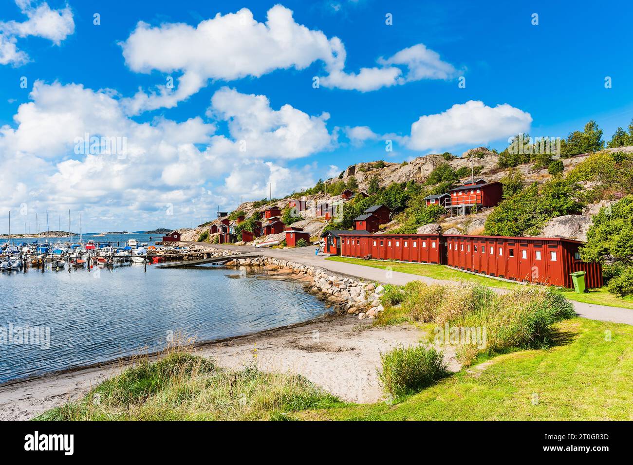 Harbor town's coastal landscape with row of red beach houses and blue sky. Stock Photo