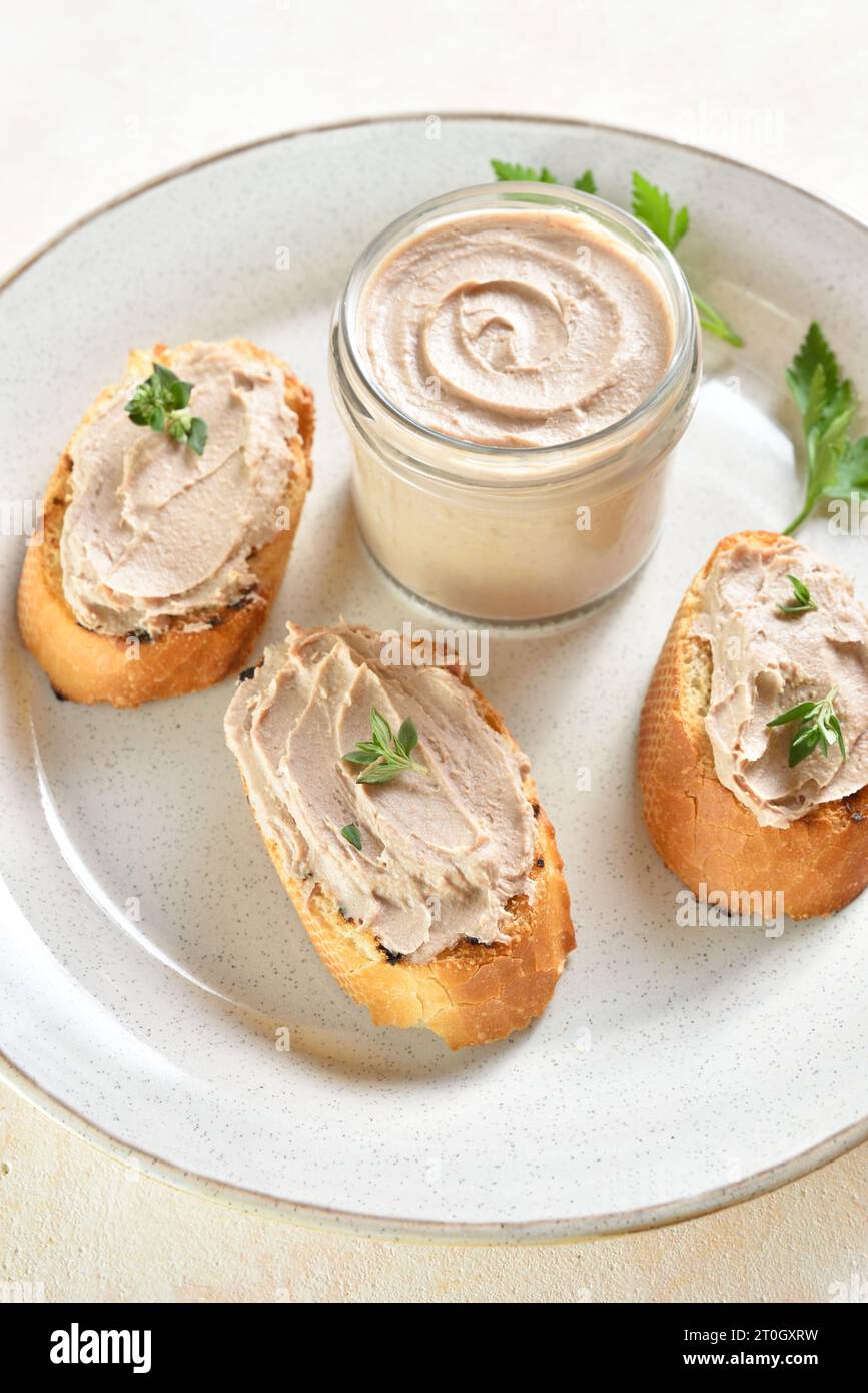Chicken liver pate on toasted bread on plate over light background. Close up view Stock Photo