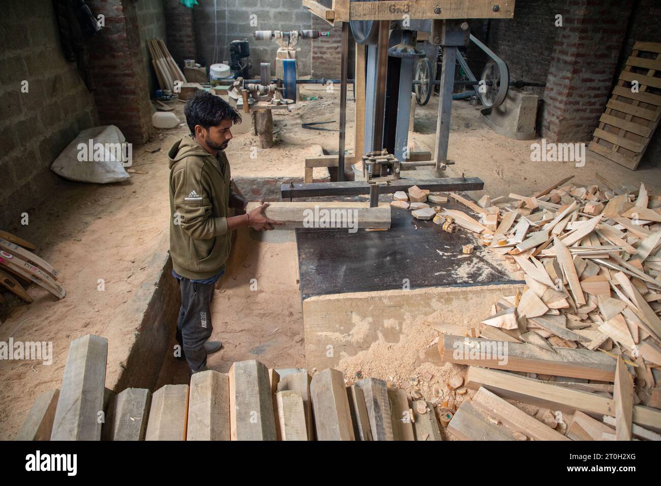 A worker shapes a willow cleft to make cricket bats at a factory in