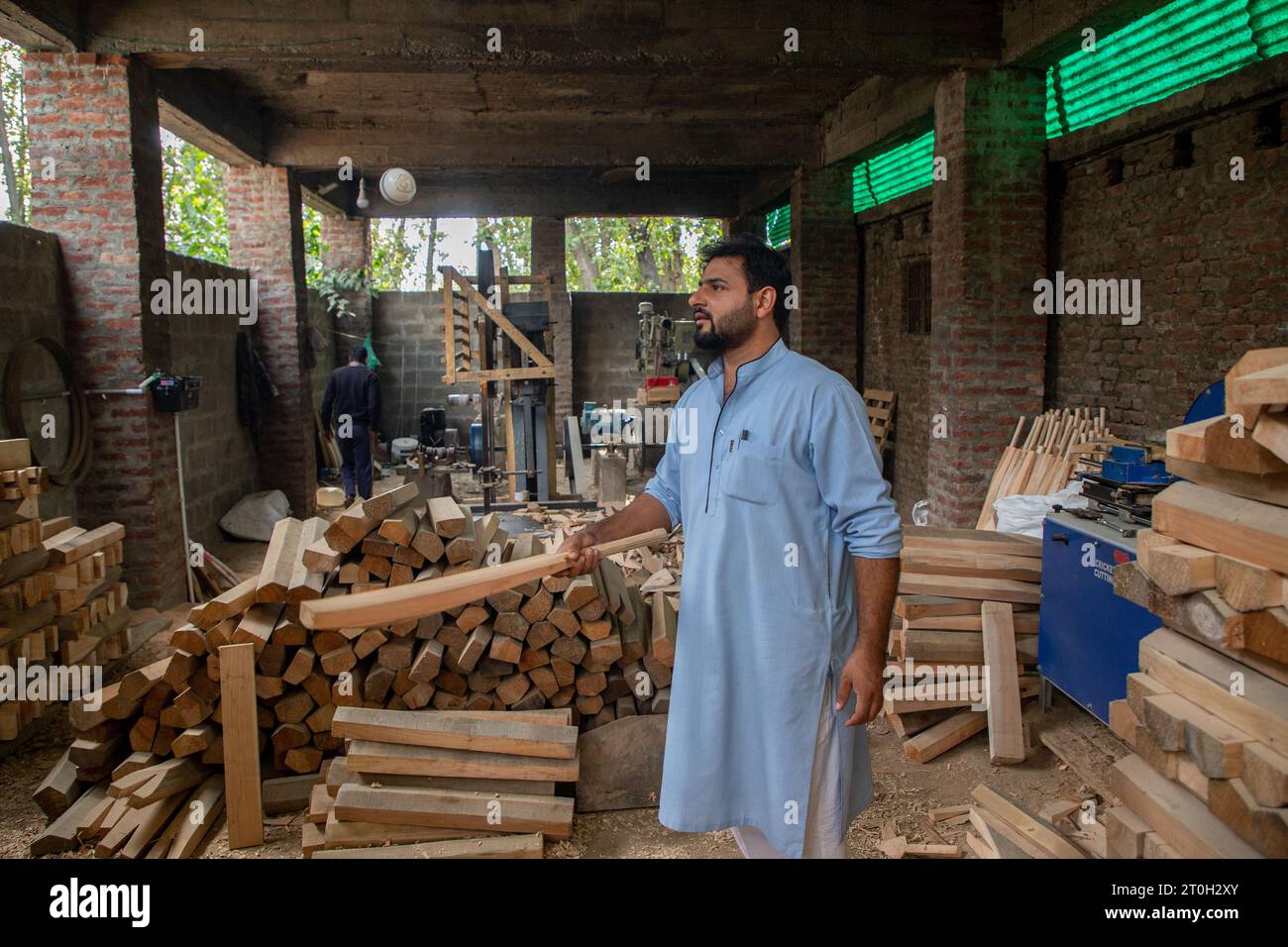 Owner of GR8 sports bat factory checks a Kashmiri willow wood cricket