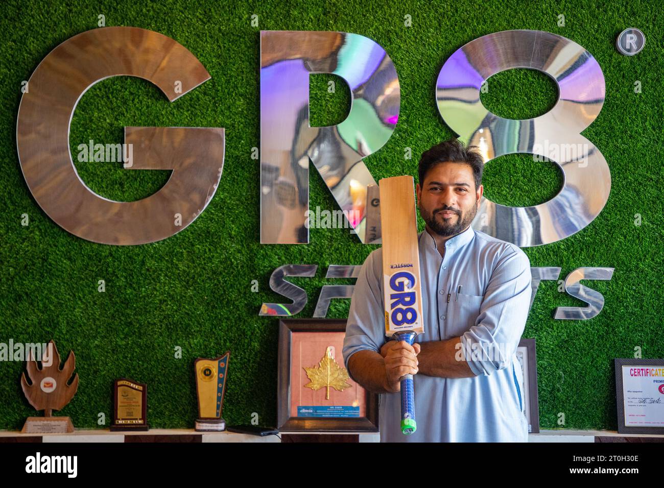 Owner of GR8 sports bat factory displays a Kashmiri willow wood cricket